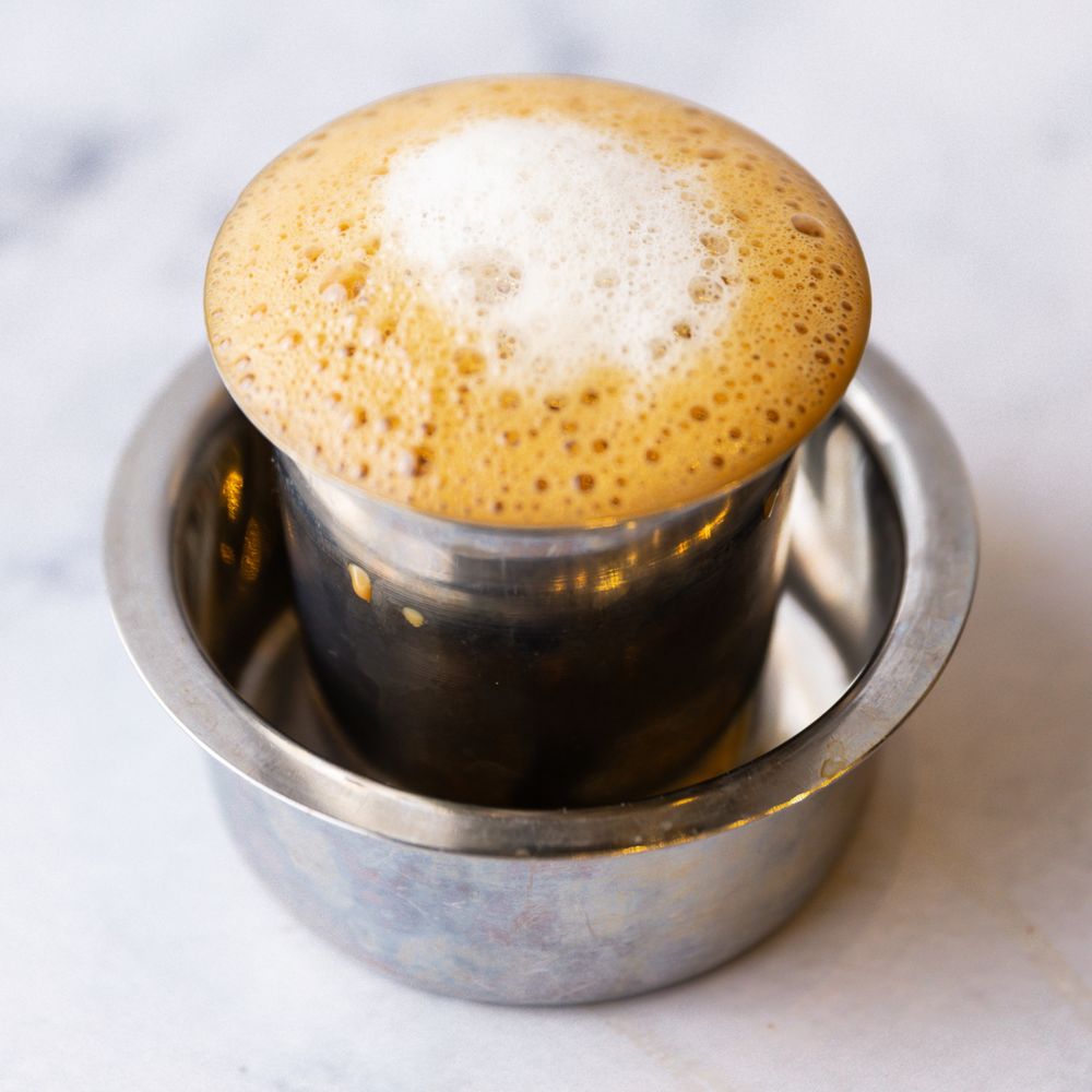 South Indian filter coffee in a steel tumbler and dabara