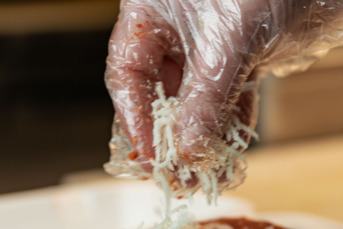 Hands at the open kitchen at Thindi Cafe, grating cheese over a toasted melt